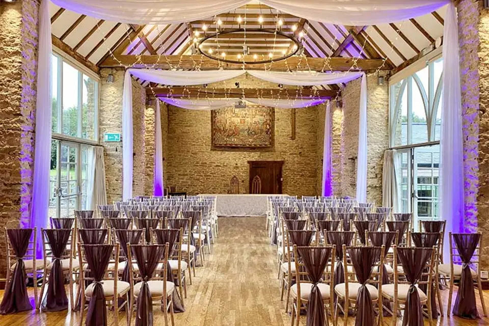 A wedding ceremony room styled with draping and warm lighting