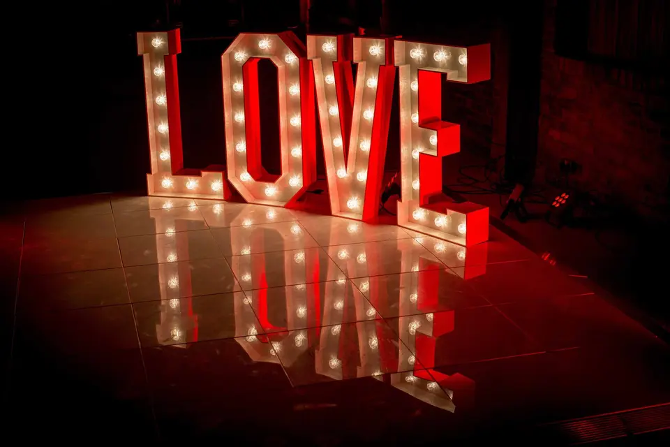 Large red light-up LOVE letters reflected on a polished floor