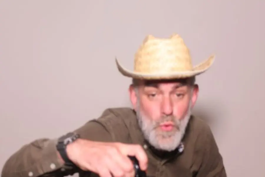 A guest in a cowboy hat leaning towards the Limelite Photobooth camera